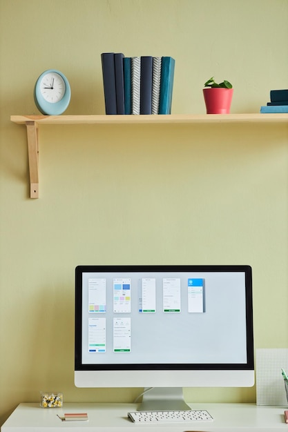 Vertical background image of minimal home office setup with computer screen and planning charts agai