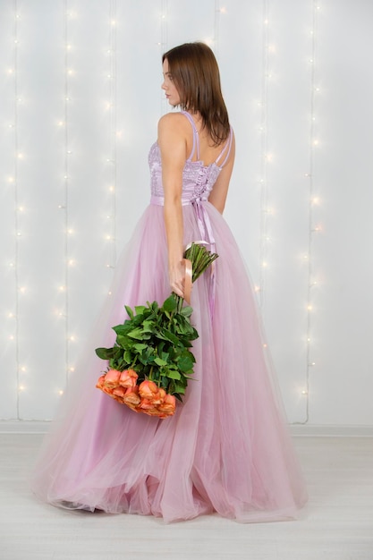 Vertical beautiful girl with a bouquet of roses in full growth