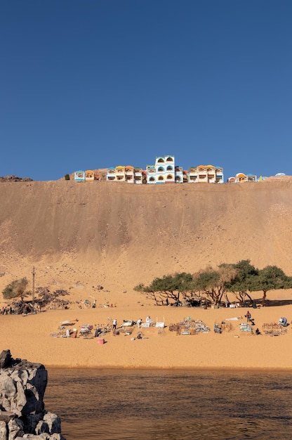 Vertical beautiful scenery of nubian colorful village on the top of sand hill with unrecognizable people selling souvenirs