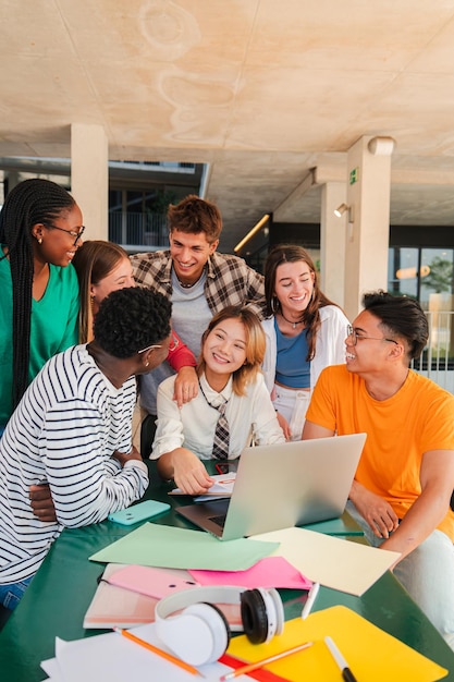 Фото Вертикальная большая группа настоящих студентов-подростков ищет информацию с помощью ноутбука в университете
