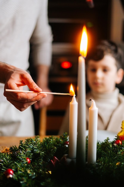 Vertical blurred closeup shot of young woman lights candles on\
dinner table served for christmas