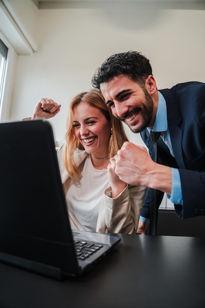 Photo vertical business people celebrating with a laptop their victory on the stock market teamwork