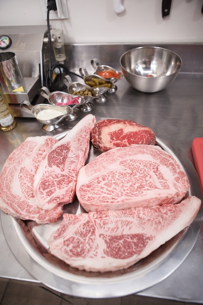 접시에 신선한 생 마블링 쇠고기 스테이크를 수직으로 닫습니다.