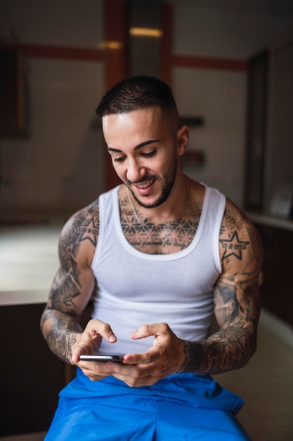Vertical closeup of a handsome tattooed guy smiling at his phone
