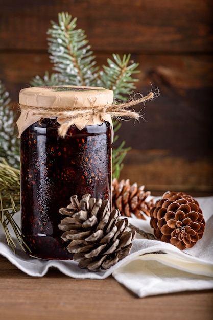 Photo vertical closeup healthy jam from pine cones in glass jar on wooden background
