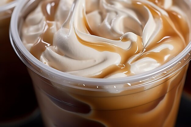 写真 バニラクリームで冷たいコーヒーのプラスチックカップの垂直クローズアップ