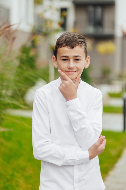 Vertical closeup portrait of a teenager in casual clothes Happy smiling teenager in autumn park in sunlight A beautiful child looks at the camera in nature