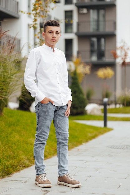 Vertical closeup portrait of a teenager in casual clothes Happy smiling teenager in autumn park in sunlight A beautiful child looks at the camera in nature