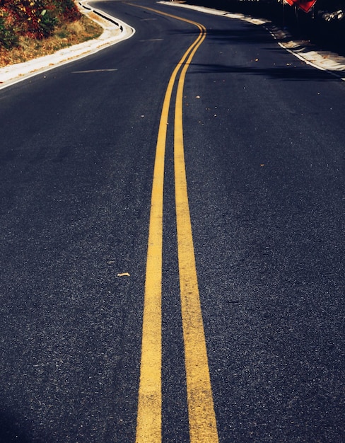 Vertical closeup shot of yellow road lines on the asphalt