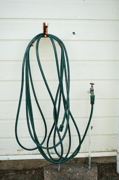 Vertical closeup of the sprinkler hose attached to the faucet outdoors