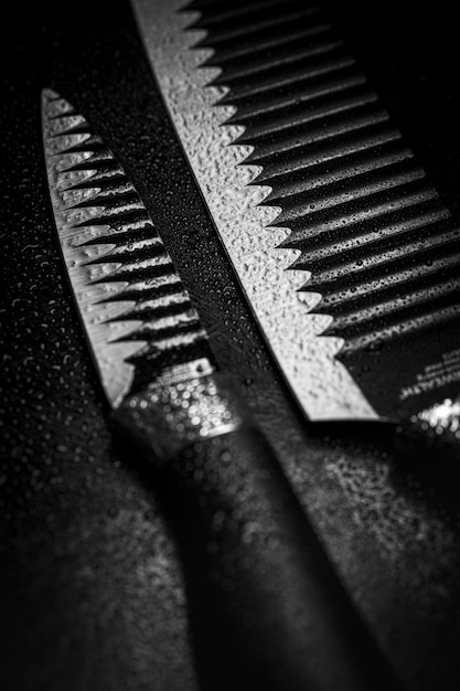 Vertical closeup of the wet knives on black background