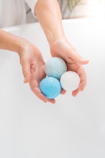 Vertical closeup of a woman39s hands putting salt and soap balls in the bathtub for skin body care