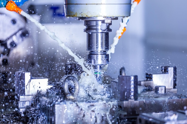 Vertical cnc steel milling process with external water coolant streams splashes and a lot of metal chips high contrast