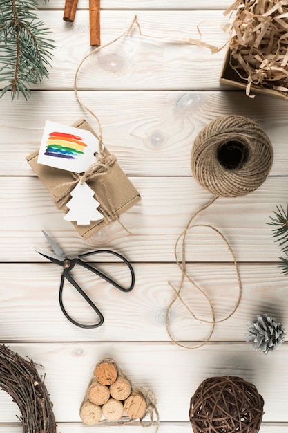 Vertical composition natural organic fabric wrapped box with rainbow label festive cards with scissors and rope sleave