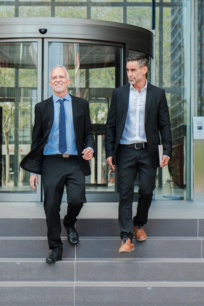 Photo vertical confident business men walking down the staircase talking about the corporate finance