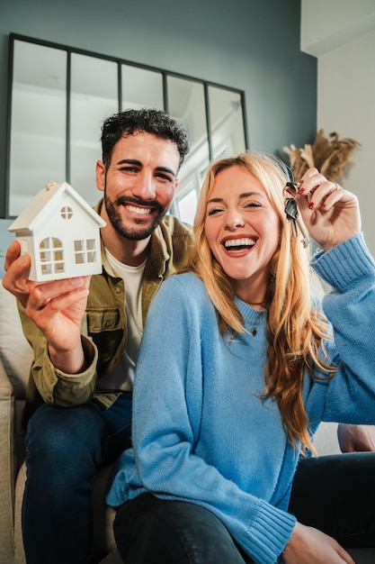 Vertical couple celebrating a beginning at their new home holding the key of the house real estate