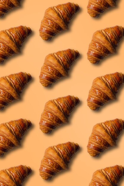 Vertical croissant pattern with orange background and copy space.