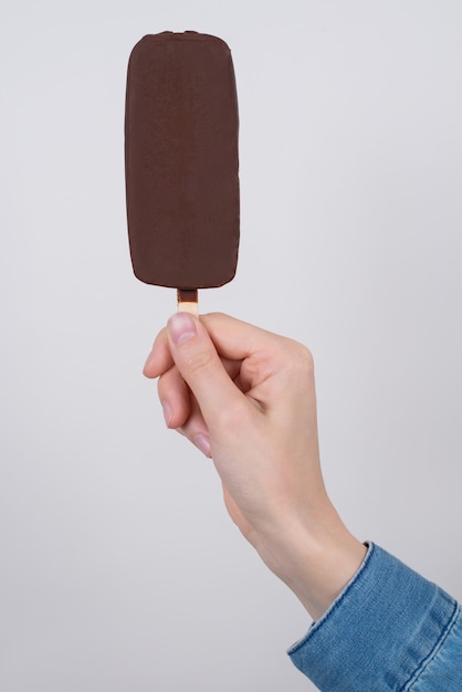 Vertical cropped close up photo of hand in casual jeans denim shirt showing giving holding taking delicious tasty ice cream isolated grey surface