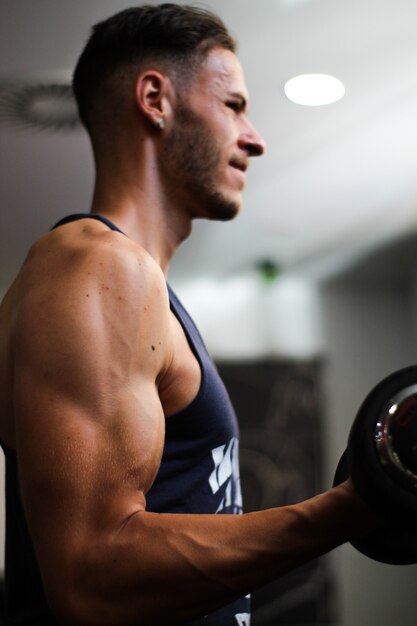 Vertical detail of a man's arm performing biceps exercise in the gym