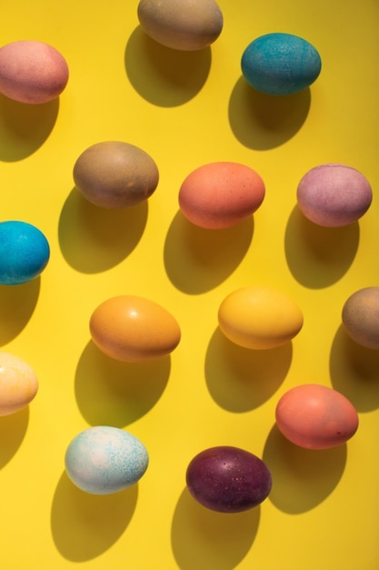 Vertical flat lay with Colorful Easter eggs on yellow background