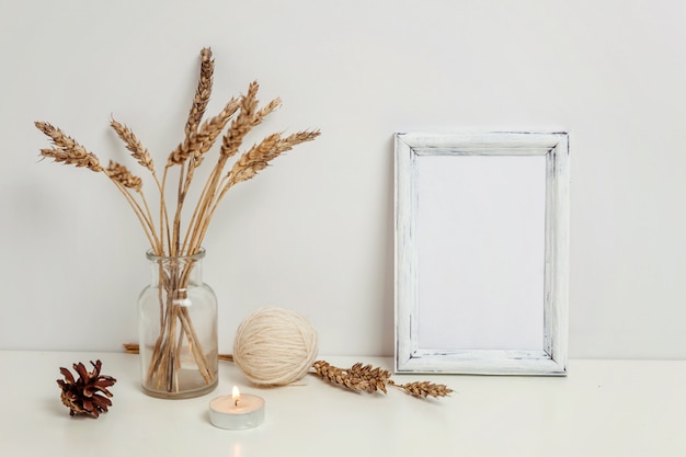 Vertical frame  with wild rye bouquet in glass vase near white wall