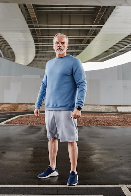 Photo vertical full length portrait of handsome senior man standing in urban city setting and looking at c