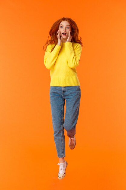 Vertical full-length portrait pretty redhead caucasian woman in casual jeans, yellow sweater