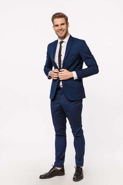 vertical, full-length shot handsome, successful and wealthy young businessman in suit and tie, fasten buttons on jacket, smiling assertive, feeling confident and lucky, determined win case in court