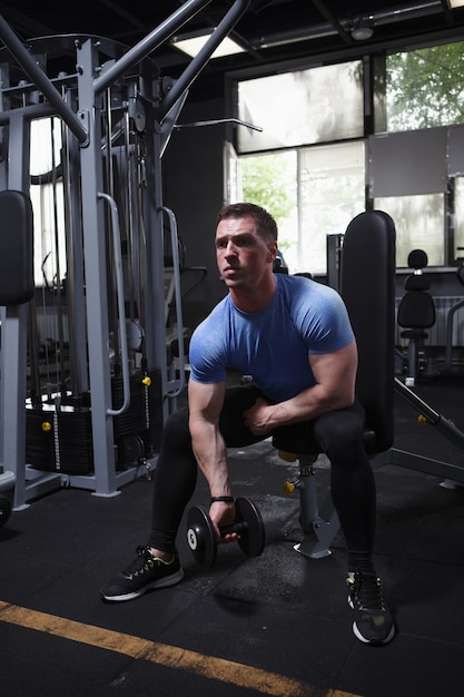 Vertical full length shot of a ripped athletic man exercising
with weights lifting dumbbell