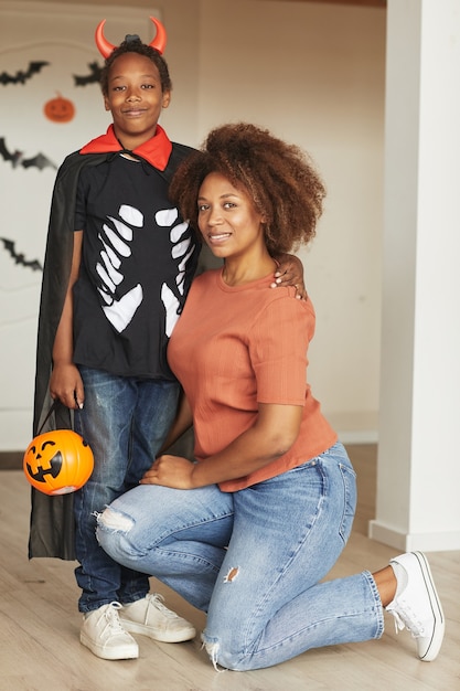 Vertical full shot of beautiful woman and her preteen son wearing little devil costume for Halloween 