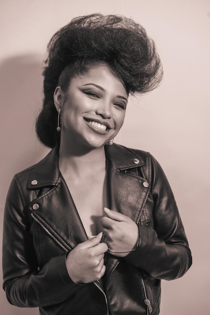 A vertical grayscale of a cute young smiling hipster female in a leather jacket