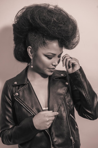 A vertical grayscale of a cute young smiling hipster female in a leather jacket