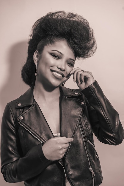 A vertical grayscale of a cute young smiling hipster female in a leather jacket