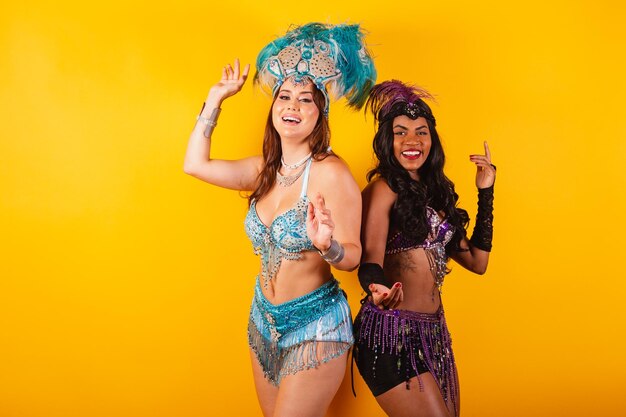 Vertical halfbody shot of two beautiful girlfriends in carnival outfits dancing