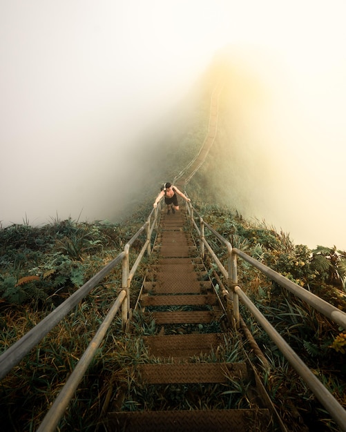 Vertical high angle shot of a male climbing up the stairs on a hill - overcoming challenges concept