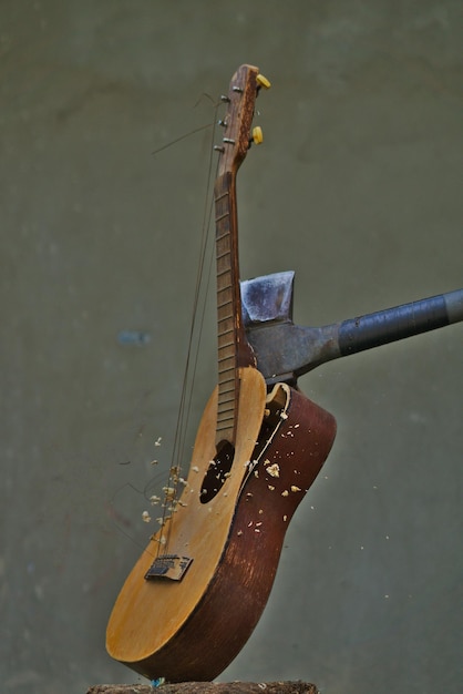 Photo vertical image of an axe smashing an acoustic guitar