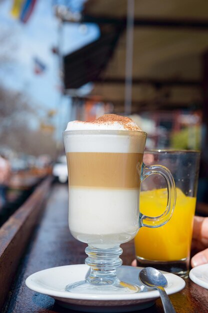 vertical image of cappuccino with foam and cinnamon in mug served at breakfast on bar outside restaurant