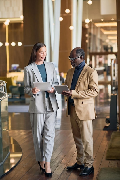 Vertical image of colleagues discussing work during meeting in the hotel