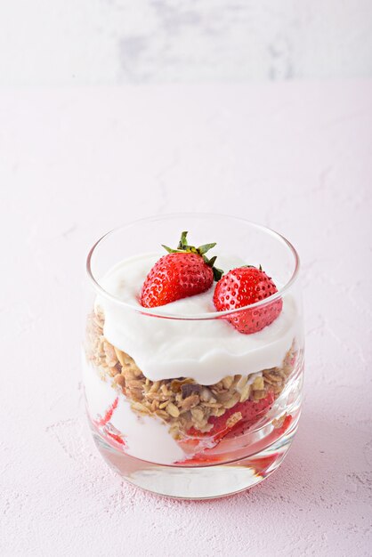 Vertical image of dessert with strawberry, granola and cottage cheese in glass