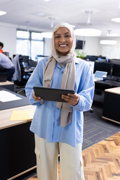 Photo vertical image of happy middleeastern businesswoman in hijab looking at camera in office