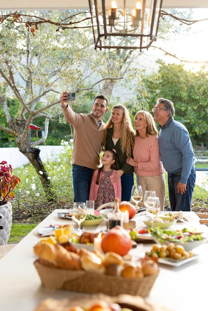 Photo vertical image of happy multi generation caucasian family taking selfie after dinner on patio. family and spending quality time together concept.