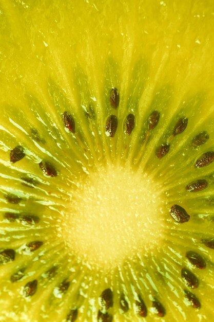 Vertical image of kiwi fruit cross section in vivid yellow color for background