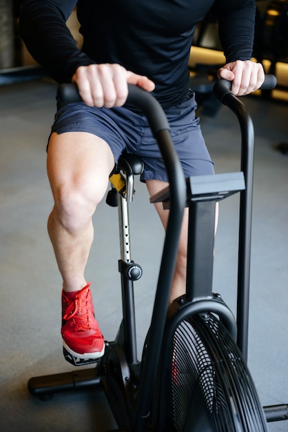 Vertical image of Muscular man using spinning bicycle