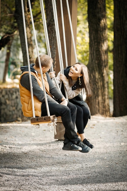 写真 暖かい季節に森林公園のブランコに乗って恋に落ちる幸せなカップルの垂直方向の画像