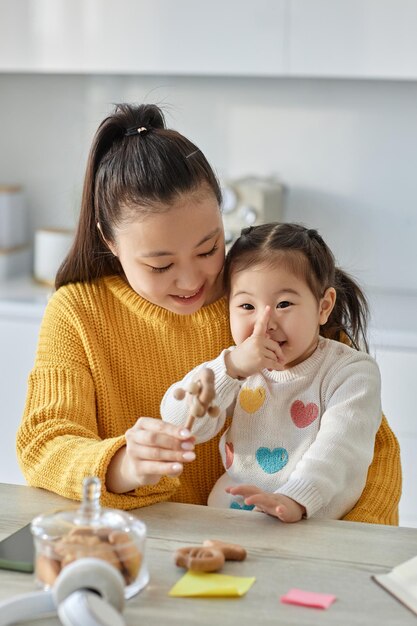 사진 부엌에서 그녀의 작은 딸과 놀고 아시아 행복 엄마의 수직 이미지