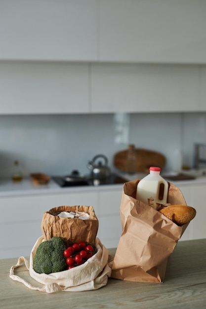 Vertical image of paper bags with products on table in the kitchen at home