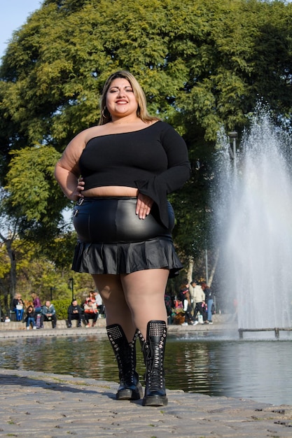 vertical image of plus size latina woman model in fashionable black clothes posing in park