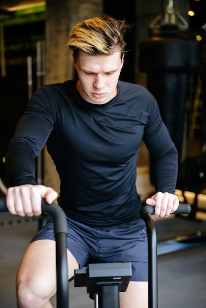 Vertical image of Serious Muscular man using spinning bicycle