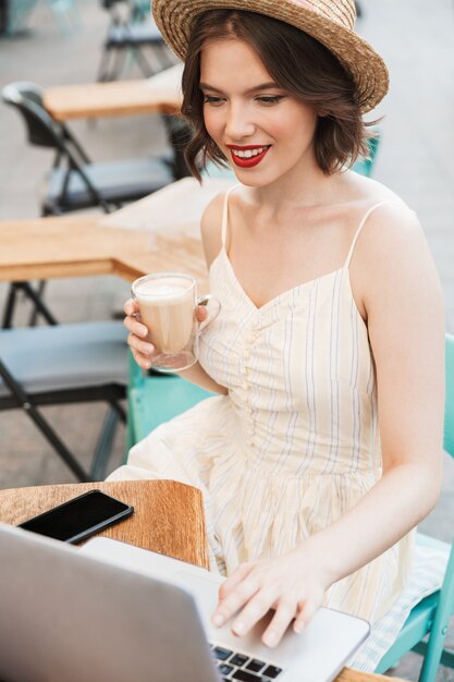 Vertical image of Smiling woman in dress and straw hat