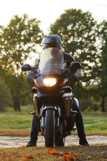 Вертикальное изображение Неузнаваемый человек на мотоцикле в природе осенью во время парковки Мотоциклетный туризм Здоровый спорт и сила характера Отличная физическая форма Оборудование мотоцикла